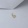 Un colgante en forma de corazón de oro con detalles de diamantes se encuentra sobre un fondo gris texturizado, mostrando la exquisita artesanía de Joyas en Oro Laminado 18K.