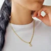 Una persona con cabello largo y oscuro que viste una camiseta blanca y un collar de oro, joyas en oro laminado de 18 quilates, parcialmente visible desde los hombros hacia arriba.