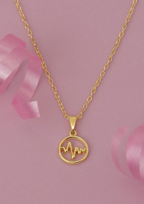 Dije Wave, un collar de oro con un colgante circular que presenta un diseño de latido de corazón, se muestra sobre un fondo rosa con detalles de cinta rosa y está elaborado con joyas bañadas en oro de 18k.