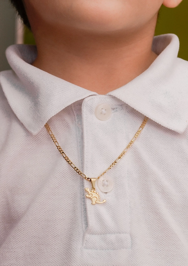 Un niño viste una camisa de cuello blanco adornada con un collar de oro con un pequeño colgante en forma de animal, elaborado con exquisitas Joyas en Oro Laminado de 18K.