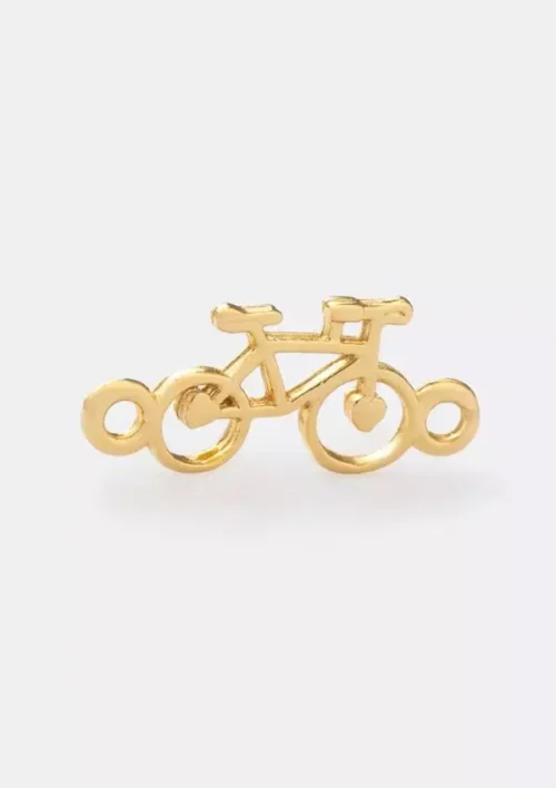 Un pequeño dije de metal de color dorado con forma de bicicleta, que presenta presillas en ambos extremos para sujetarlo, que recuerda a la bicicleta de Herraje.