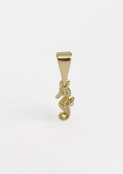 Un pequeño dije de caballito de mar en oro con un lazo en la parte superior para sujetarlo, elaborado en Joyas en Oro Laminado 18K.