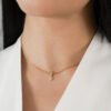 Primer plano de una persona que lleva un collar de oro con las iniciales "J" y "R" en una cadena de oro. La persona lleva una camiseta blanca, que muestra exquisitas joyas en oro laminado de 18k.