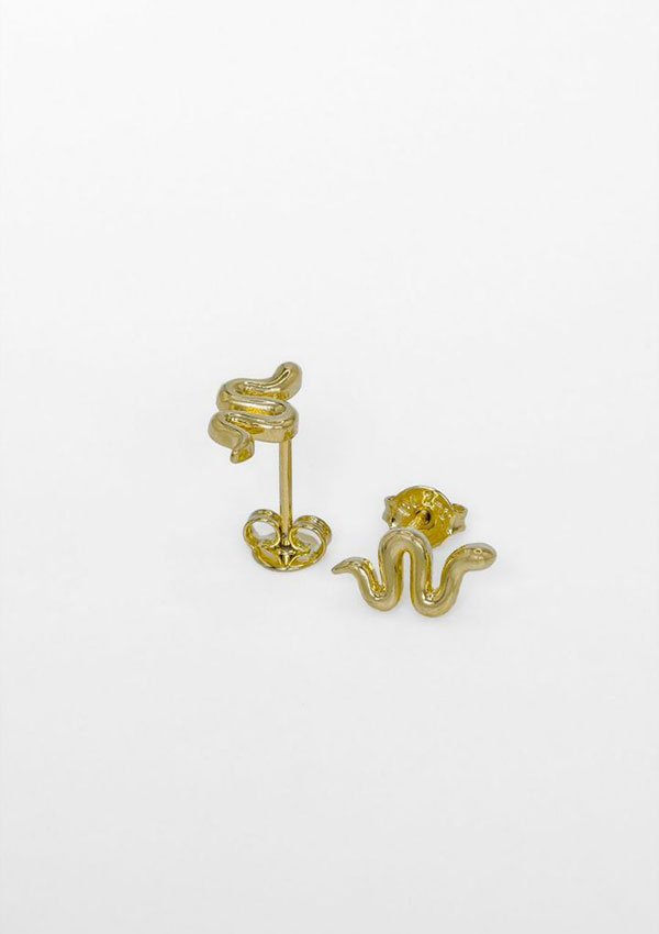 Un par de pendientes Aretes Snake oro laminado 18K, uno con gancho y el otro con tachuela, sobre un fondo blanco liso.