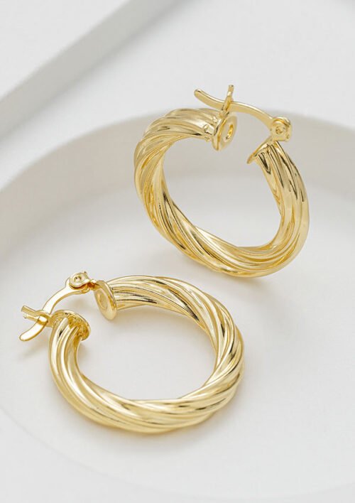 Par de aretes de aro trenzados Candongas Twisted Stripes de oro de 18 quilates con cierre de pestillo, exhibidos sobre una superficie blanca. Estas impresionantes joyas añaden un toque de elegancia a cualquier conjunto.