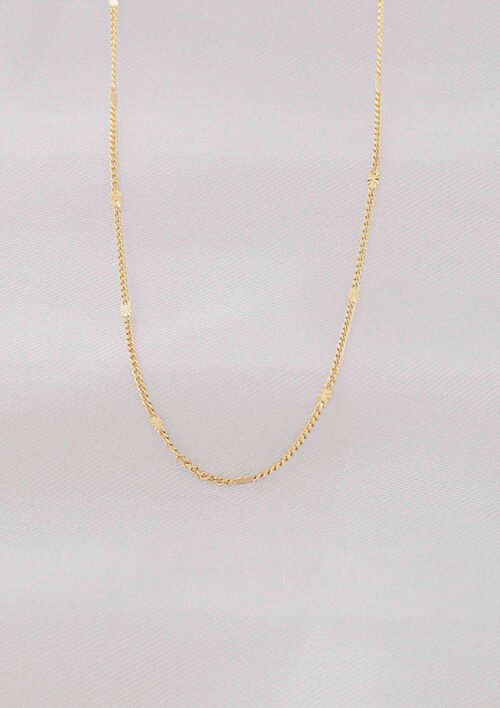 Un delicado collar de cadena bañado en oro de 18k, Cadena Cubana Con Destellos 60 Cm, mostrado sobre un fondo gris claro.