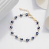 Pulsera Ojo Turco 16 Cms + Extensor que presenta una pulsera de cadena de oro adornada con cuentas azules y blancas en forma de ojos, elegantemente dispuestas sobre una superficie blanca plana con elementos decorativos en el fondo. Esta impresionante pieza es parte de nuestra colección Joyas en oro laminado de 18k, que ofrece elegancia y belleza atemporal.