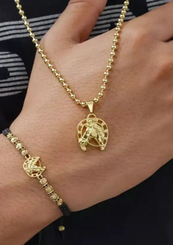 Persona que lleva un collar colgante de caballo dorado y una pulsera de cuentas a juego.