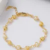 Pulsera de oro con perlas redondas alternadas y cuentas de oro texturizadas sobre una superficie plana.