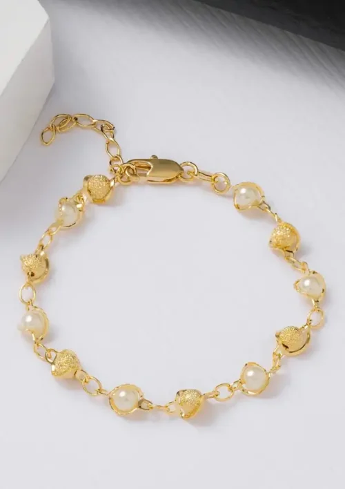 Pulsera de oro con perlas redondas alternadas y cuentas de oro texturizadas sobre una superficie plana.