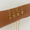 Un antebrazo que exhibe cuatro collares de oro "Dije Diamante", cada uno con un colgante en forma de diamante en una cadena de oro.