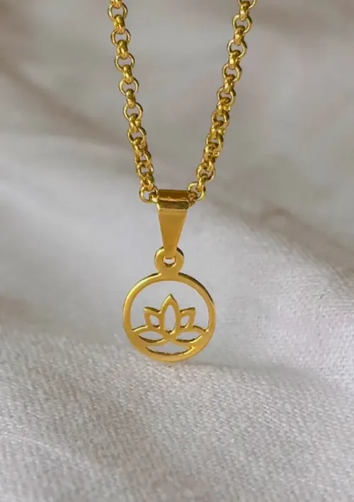 Collar de oro que presenta el Dije Flor de Loto, un colgante circular con un diseño de loto recortado, expuesto sobre un fondo de tela clara.