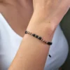 Una persona que lleva la Pulsera Infinito, una pulsera de cuentas negras y doradas, en su muñeca.