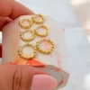 Una mano sostiene un objeto hexagonal jaspeado que muestra seis aros de oro con detalles de cuentas, llamados CANDONGA ESFERA G.