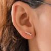 Primer plano de una oreja adornada con cinco Aretes Guadalupe Finita, pequeños aretes en forma de estrella a lo largo del lóbulo de la oreja.